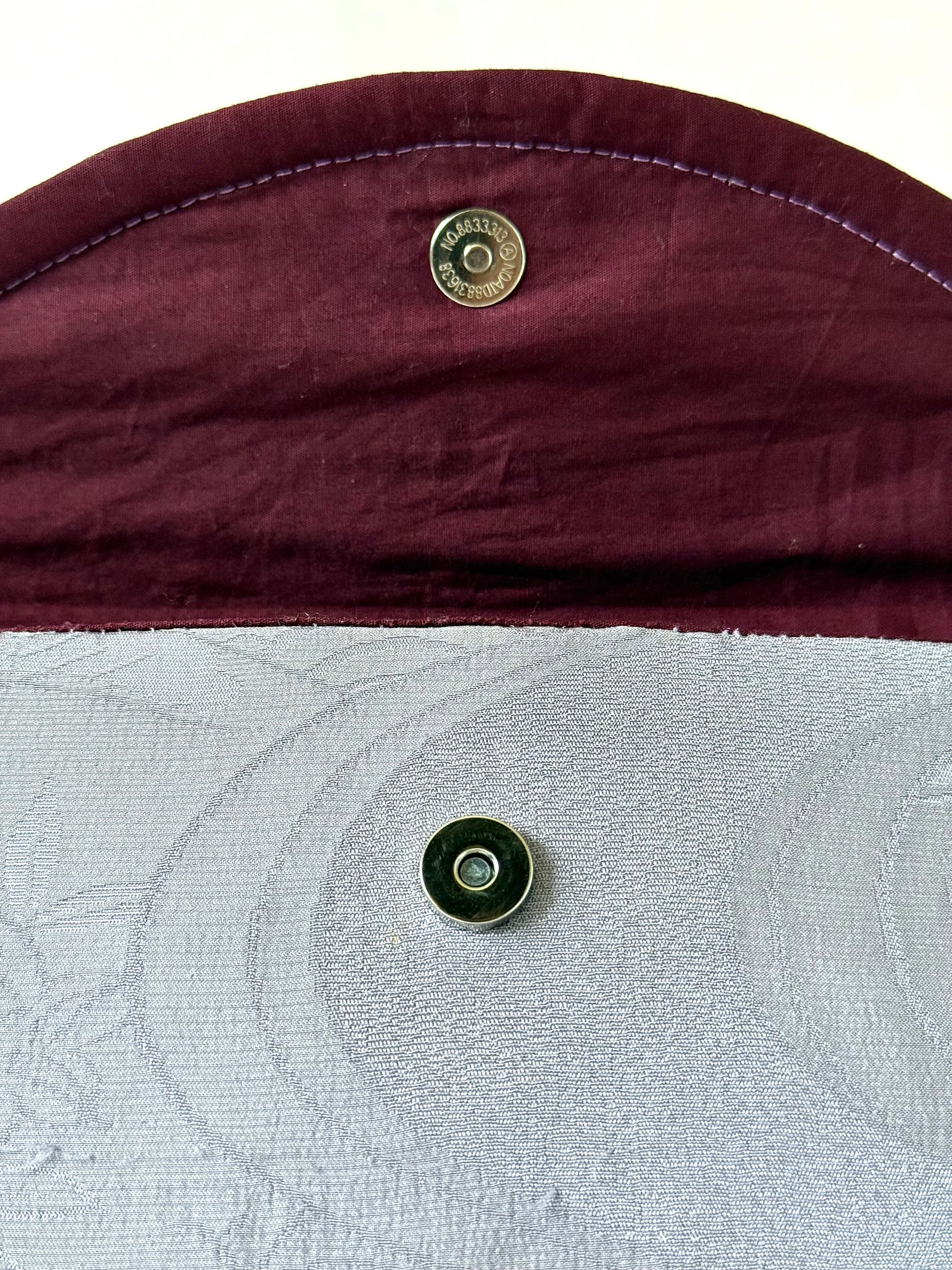 Close up of magnetic closure on the flap of handmade fold over clutch bag