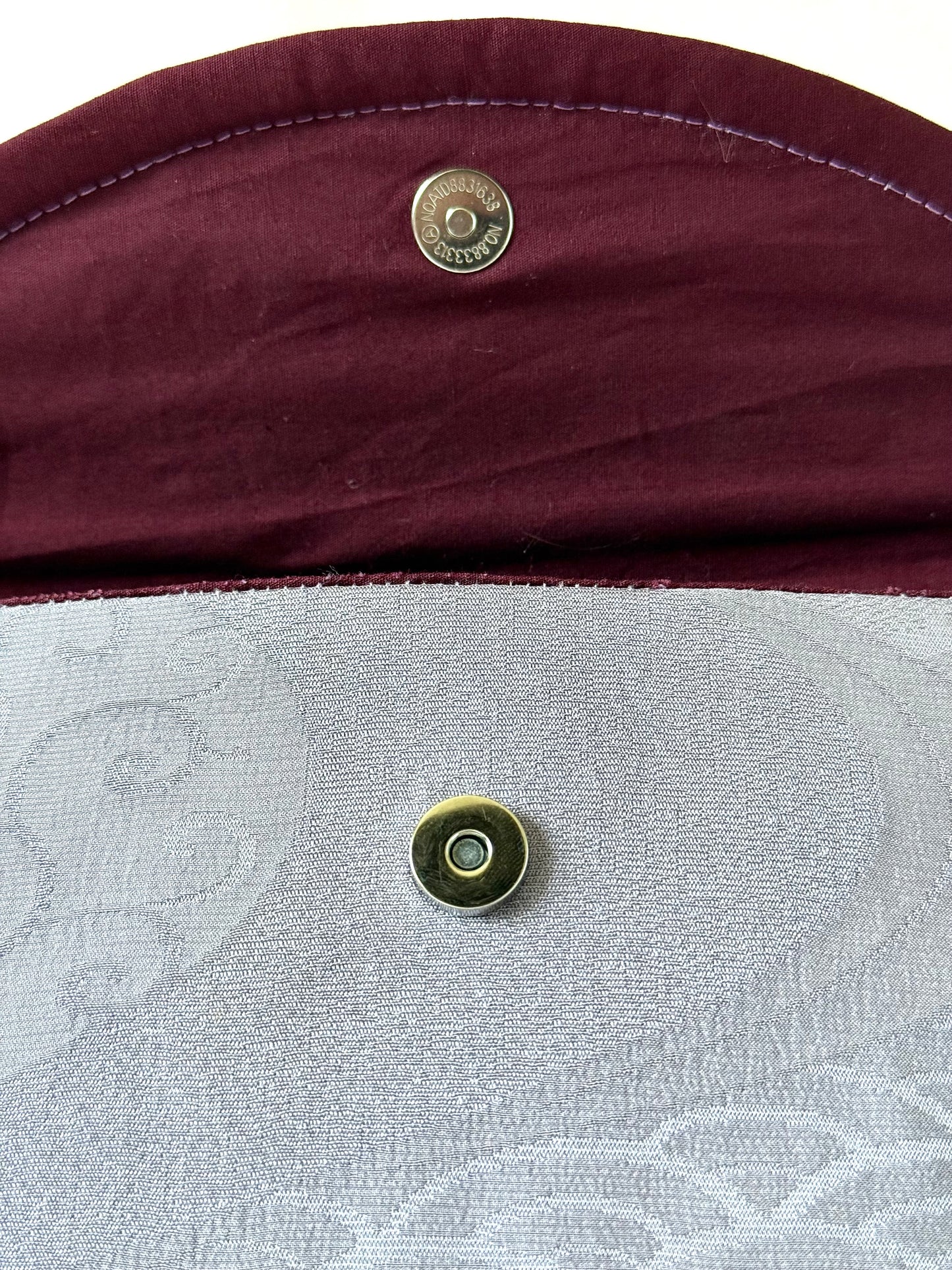 Close up of magnetic closure on main body and wine colored cotton broadcloth interior with purple top stitching