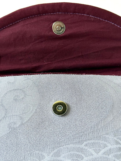 Close up of magnetic closure on main body and wine colored cotton broadcloth interior with purple top stitching