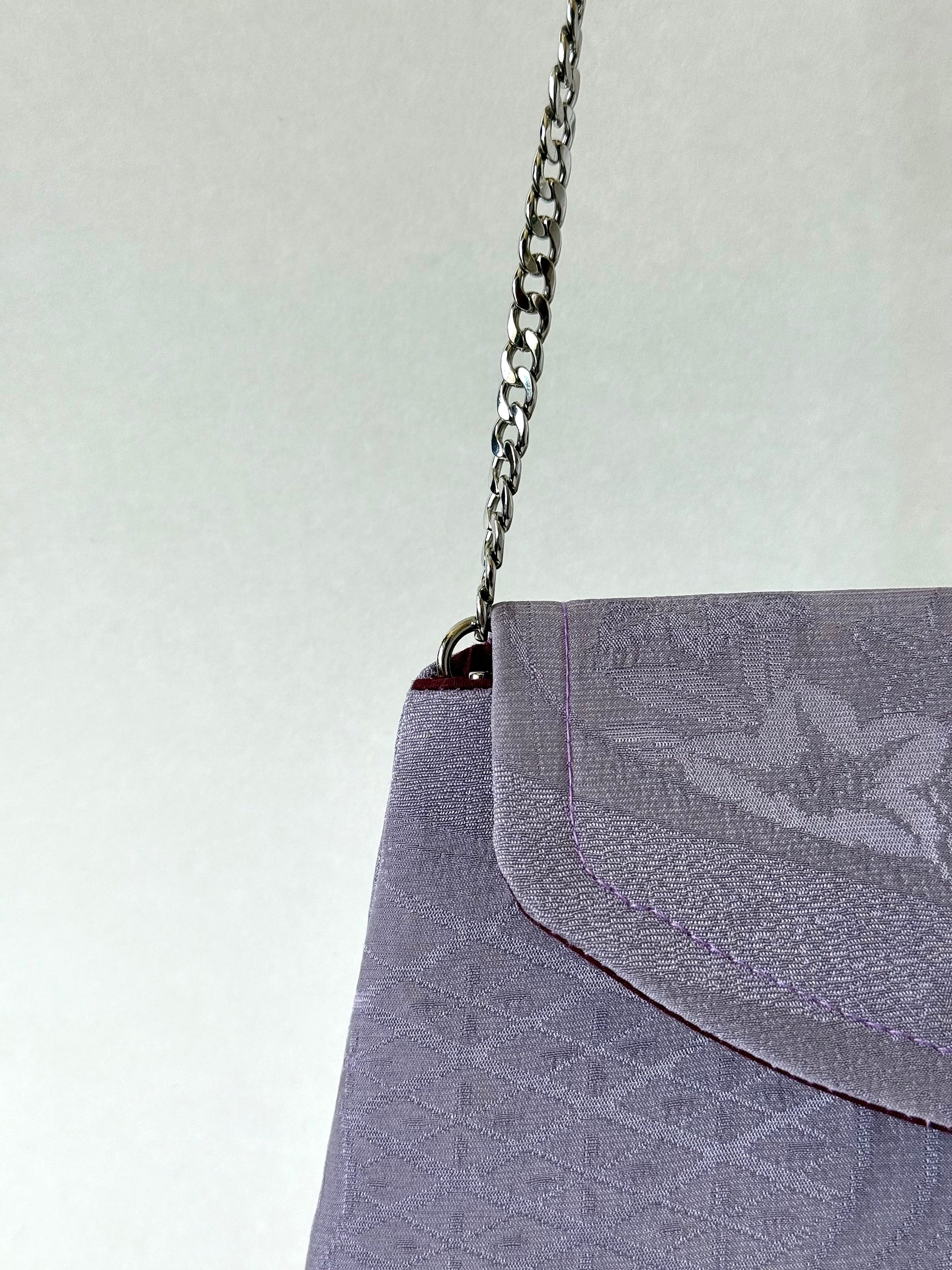 Close up of metal chain strap discreetly attached to the interior of pink chirimen silk clutch