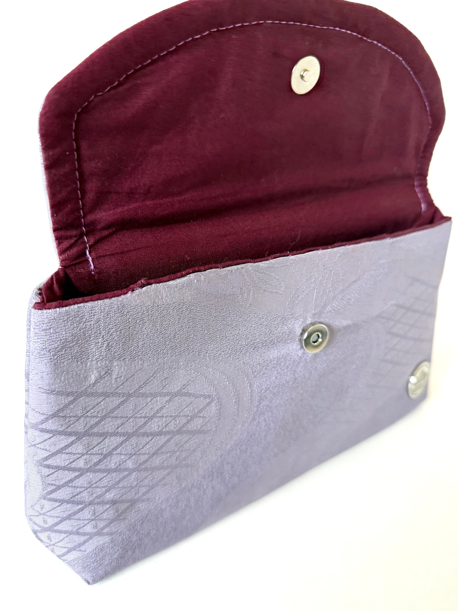 Close up view of hand sewn seam connecting wine colored cotton broadcloth interior and purple kimono silk exterior of a clutch bag