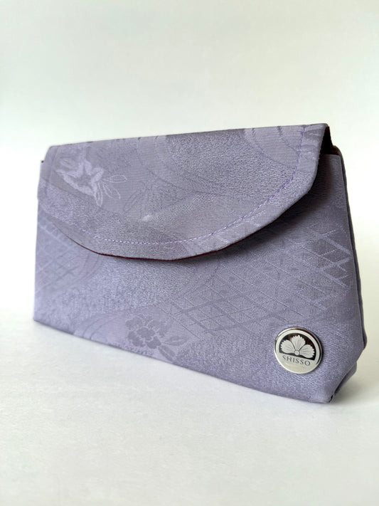 Front view of purple chirimen silk clutch with floral, geometric, and river motifs