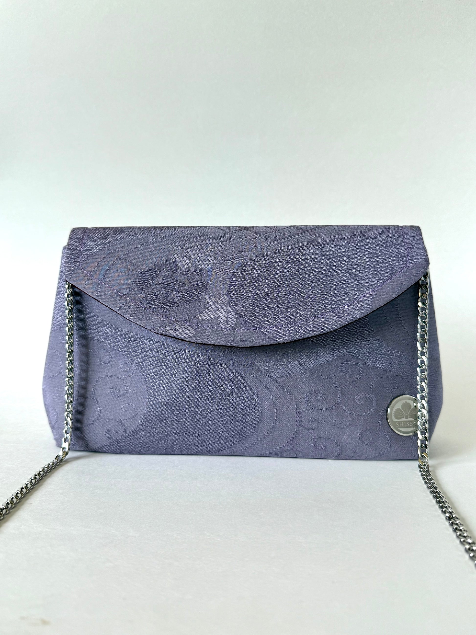 Front view of purple crepe textured kimono silk clutch with silver colored metal chain attached to the interior sides