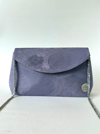 Front view of purple crepe textured kimono silk clutch with silver colored metal chain attached to the interior sides