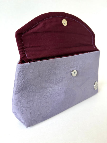 Opened flap on purple kimono silk fold-over clutch bag showing hand sewn seam and wine colored broadcloth interior lining