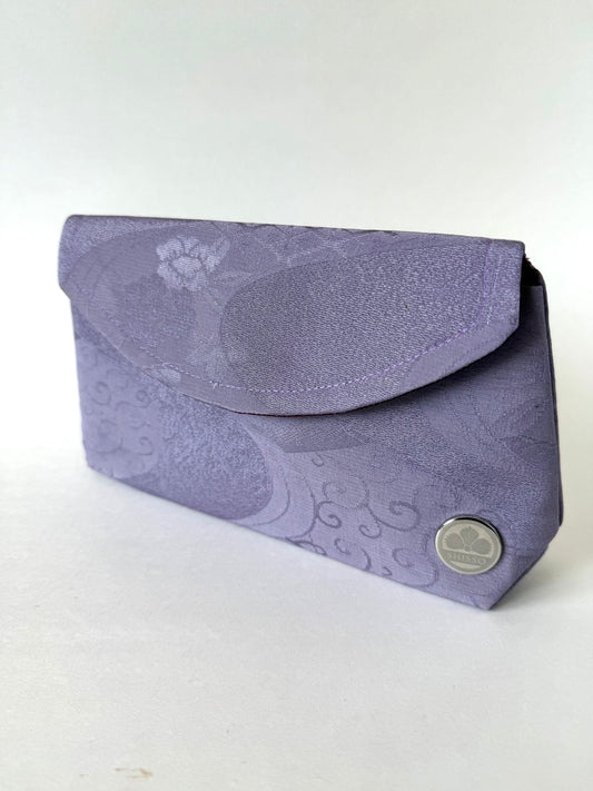 Front angled view of purple, crepe textured kimono silk fold-over clutch with floral and flowing water motifs