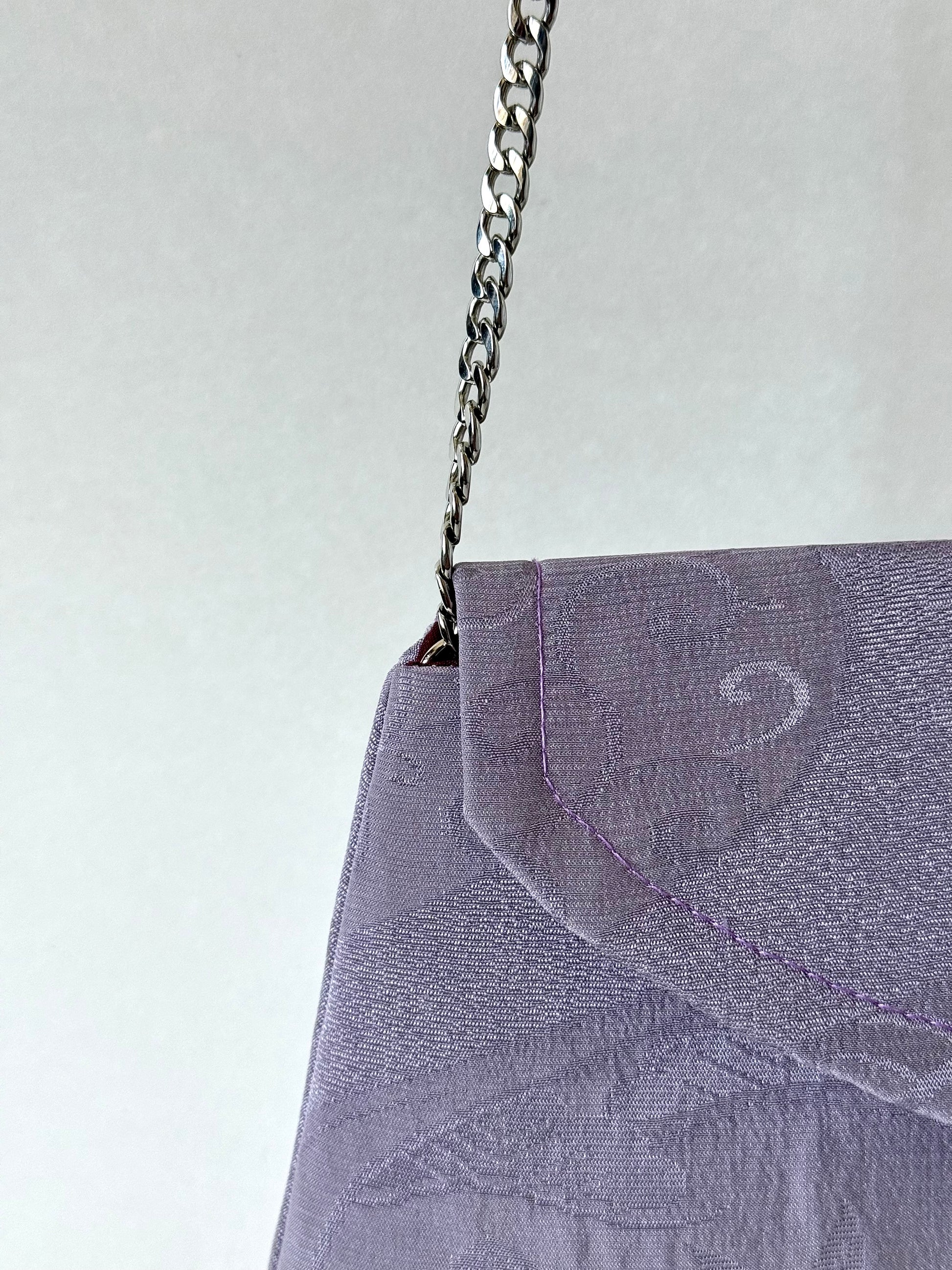 Thing metal chain strap connected to the interior corned of purple kimono chirmen silk clutch bag