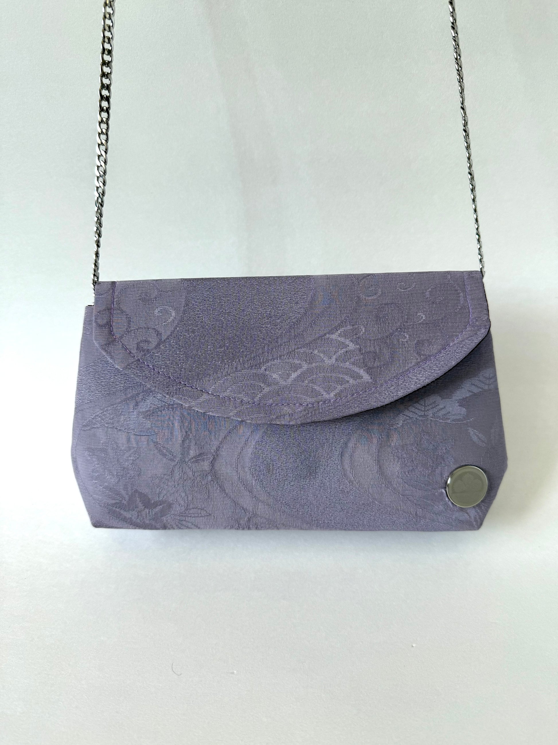Front view of purple kimono silk clutch bag hanging from elegant metal chain strap