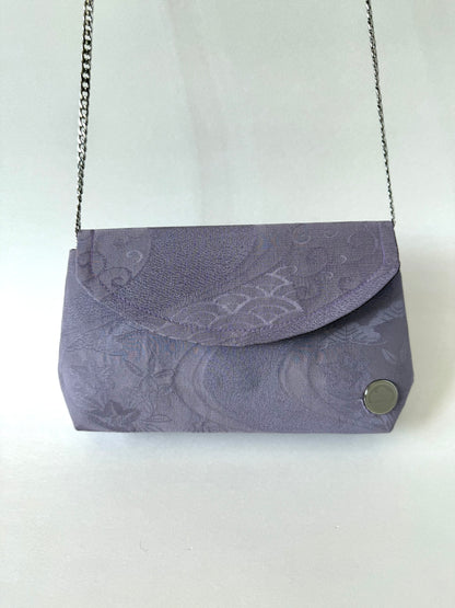Front view of purple kimono silk clutch bag hanging from elegant metal chain strap