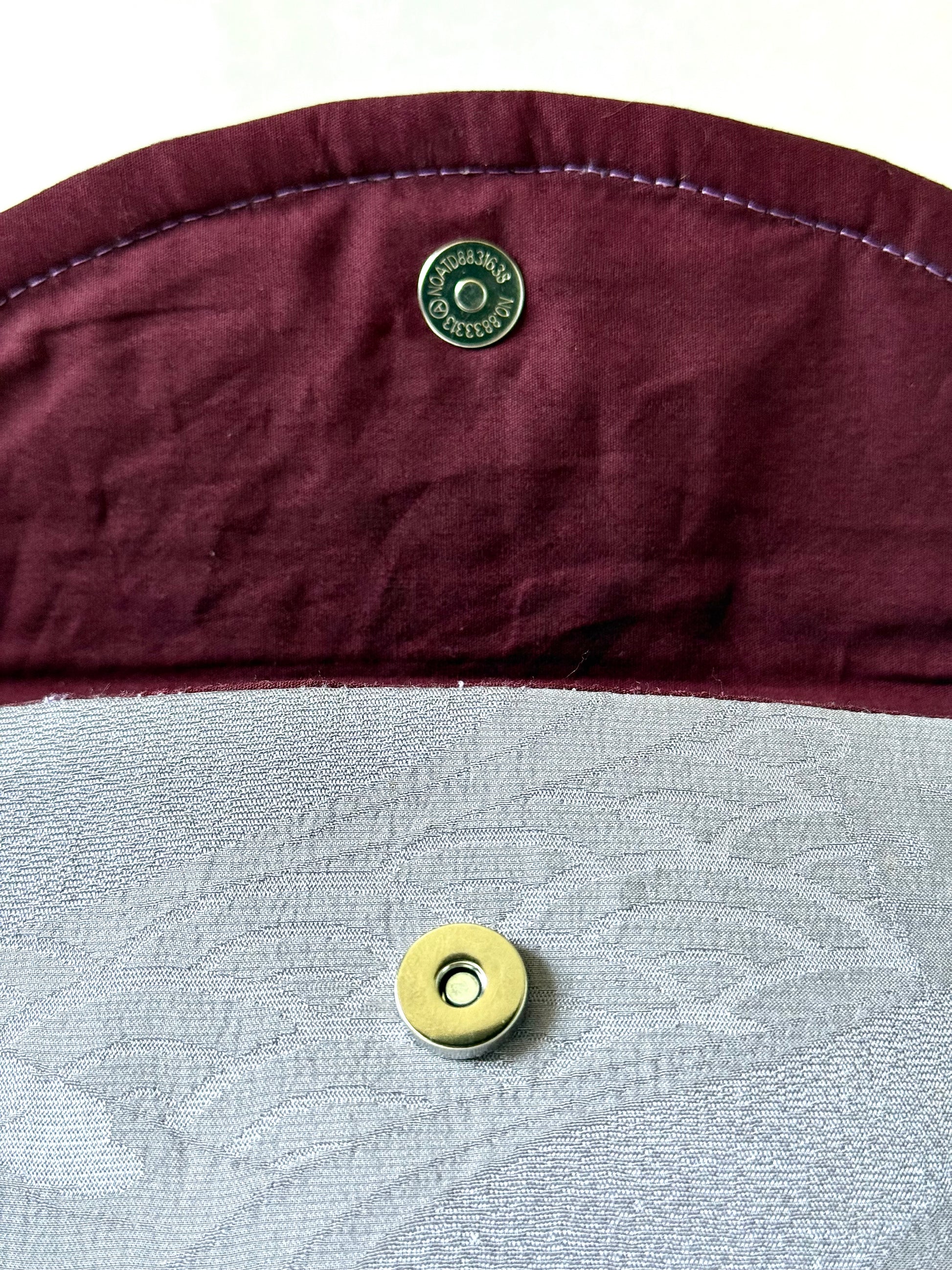 Close up view of magnetic closure over seigaiha motif and under hand stitched seam