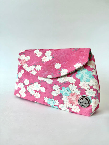 Front angled view of pink kimono silk clutch bag with cherry blossoms