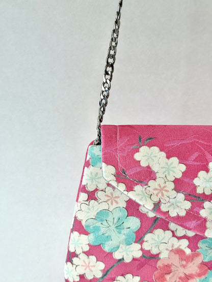 Silver colored metal chain strap on pink clutch bag with sakura motif
