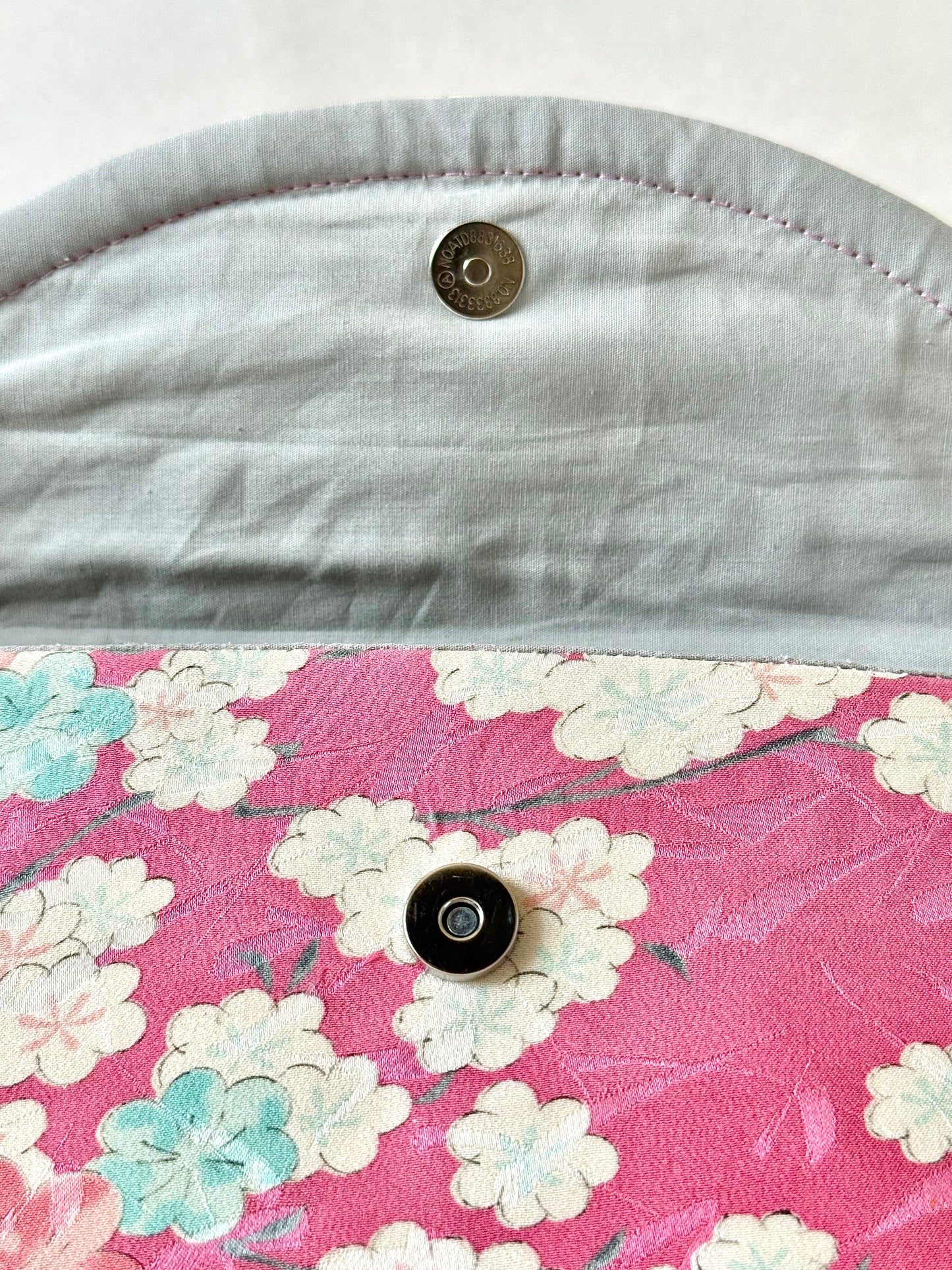 Magnetic flap closure on cherry blossom clutch bag with silver cotton broadcloth interior