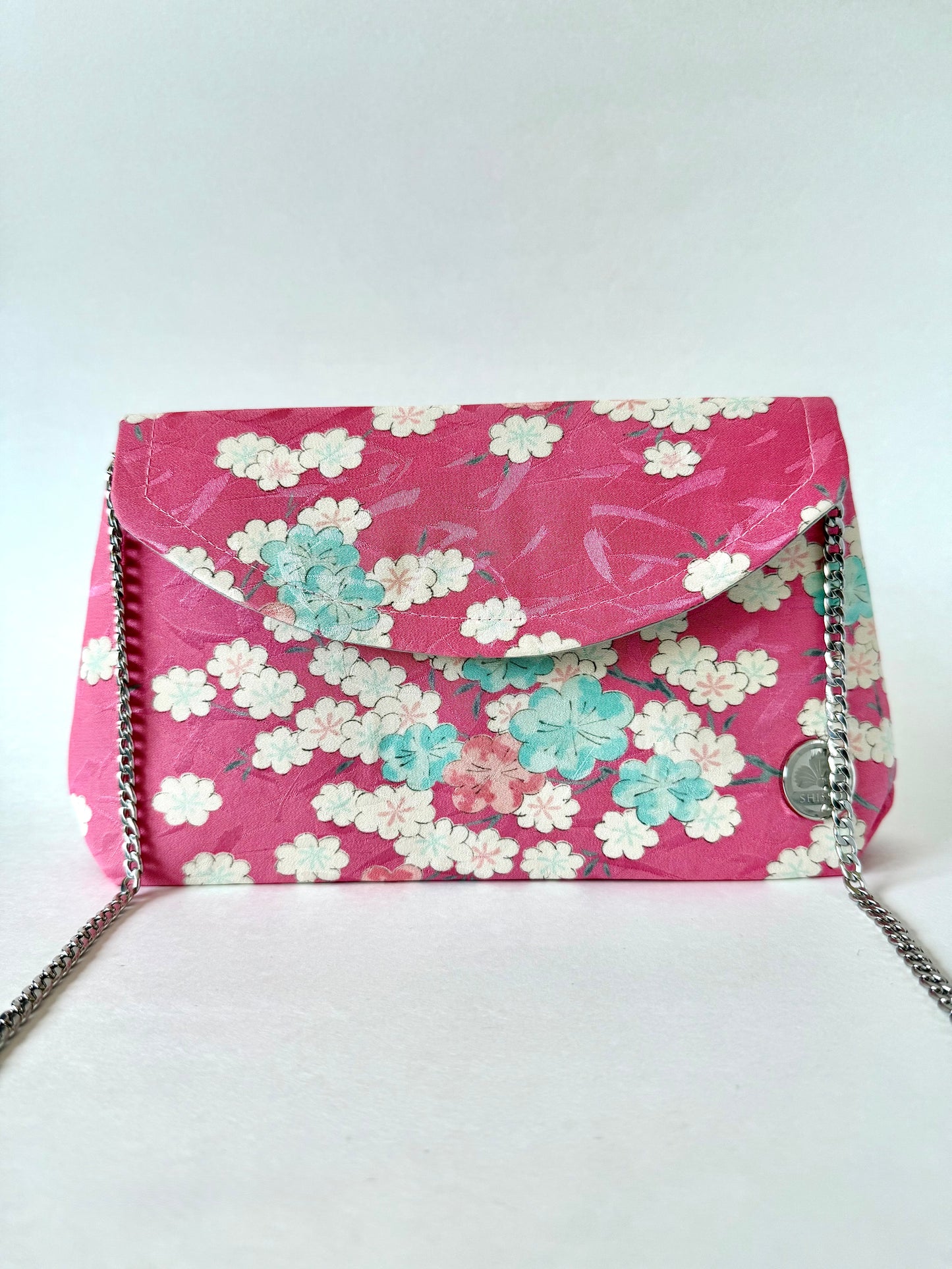 Pink kimono silk clutch bag featuring multi colored cherry blossoms and silver colored chain strap
