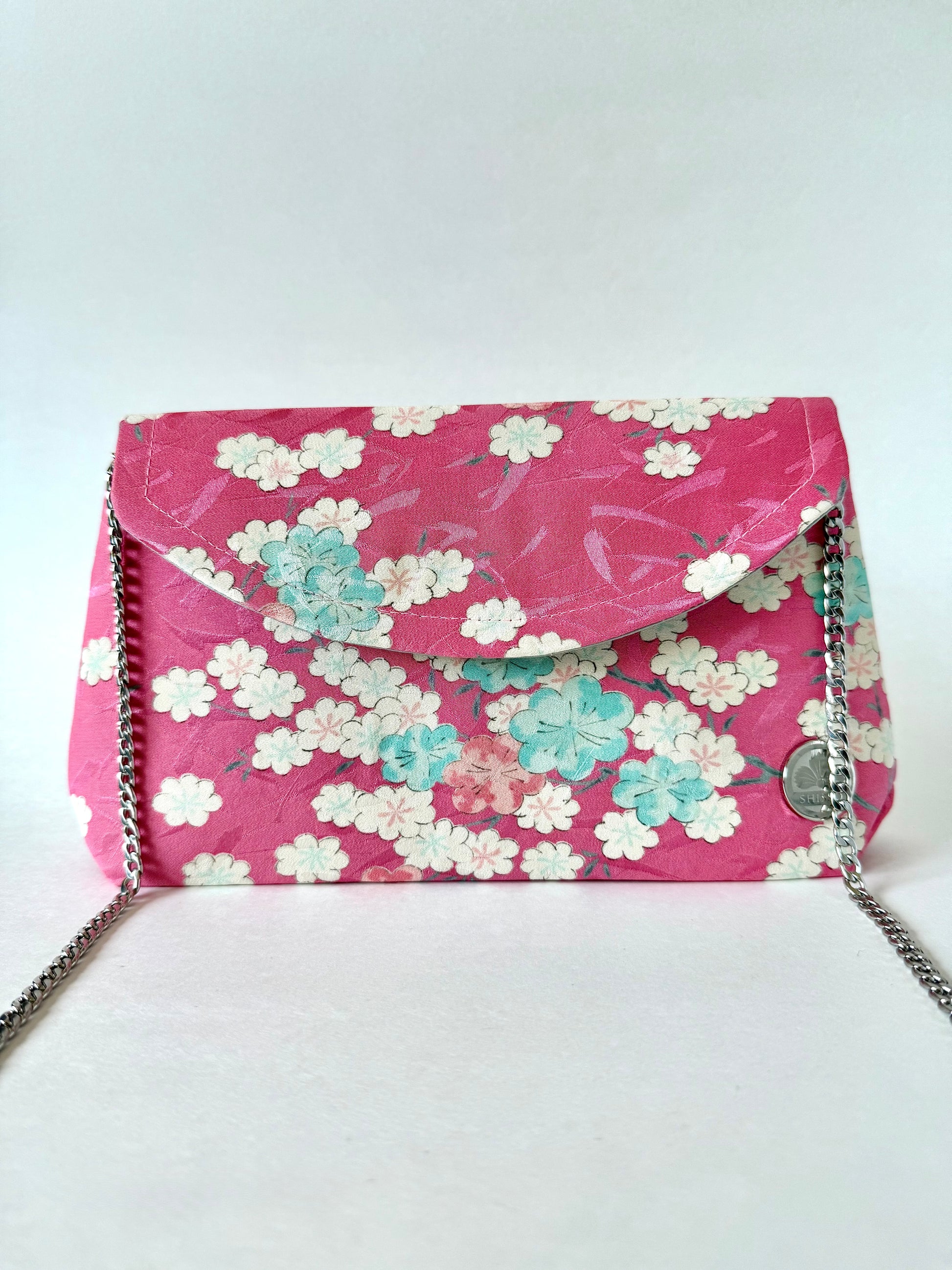 Pink kimono silk clutch bag featuring multi colored cherry blossoms and silver colored chain strap