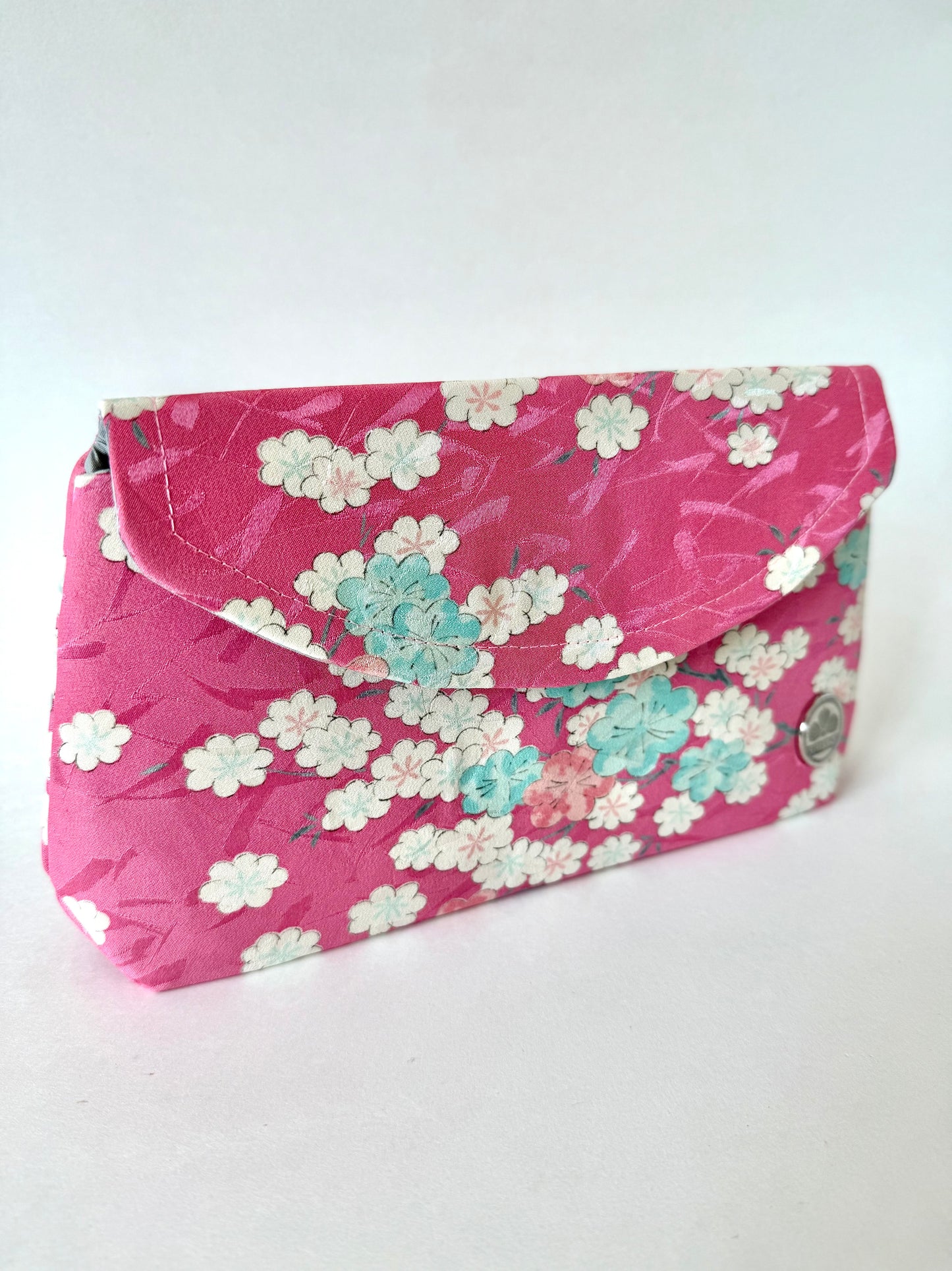 Clutch bag made with pink kimono silk featuring blooming sakura flowers in pink, blue, and white