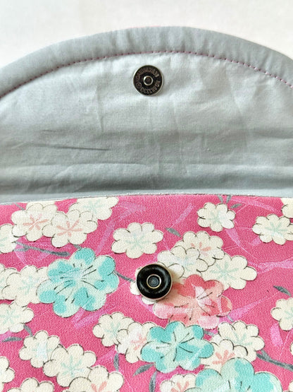 Silver colored magnetic closure on foldover clutch bag with cherry blossom flower motif