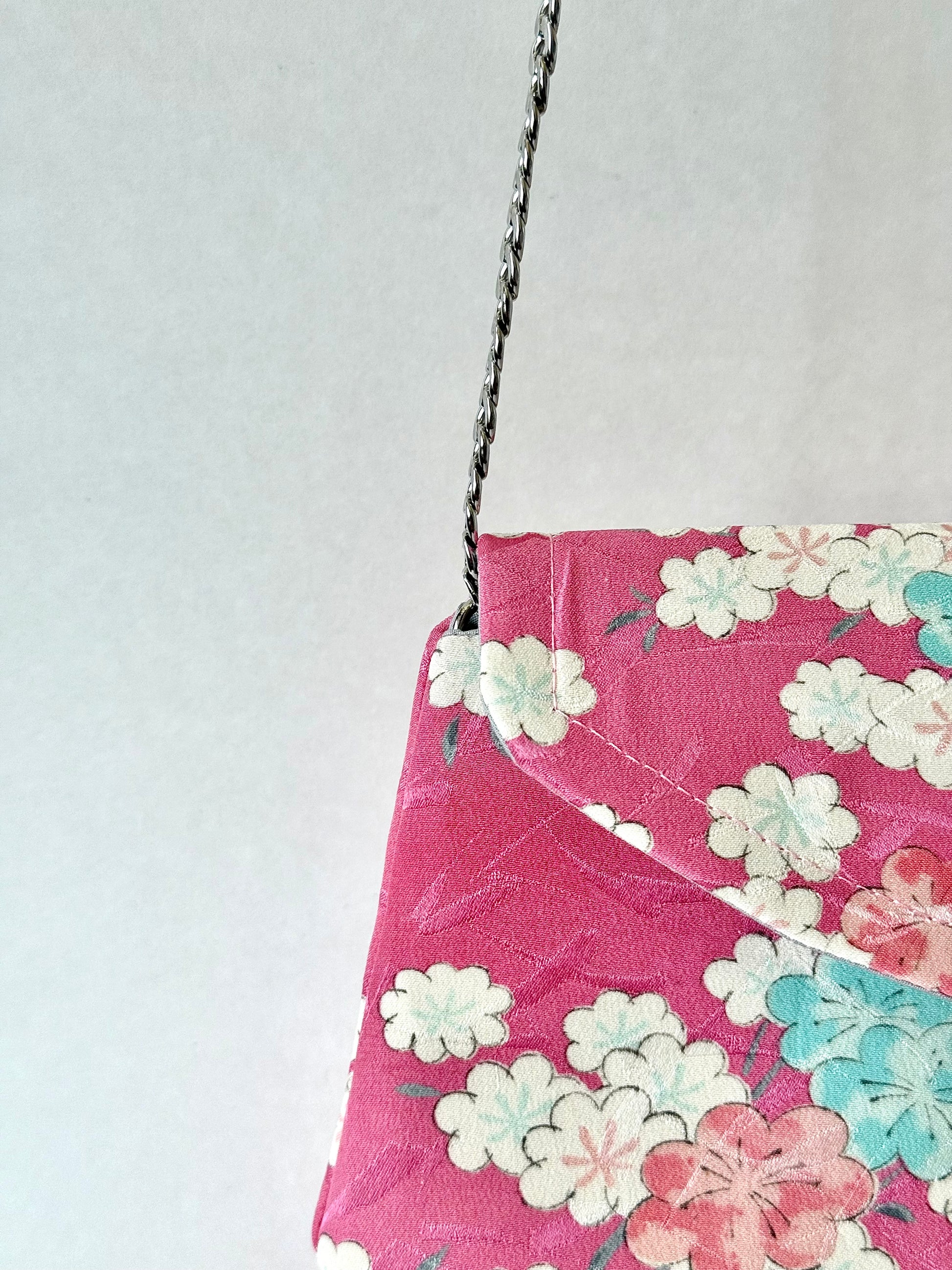 Metal chain strap discretely connected to handmade clutch bag with sakura motif