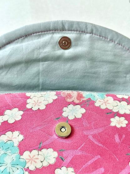 Silver colored magnetic closure on pink kimono silk clutch bag with sakura motif and shiny brush stroke like accents