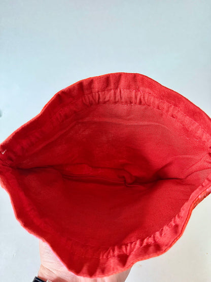 Top view of opened kimono silk drawstring pouch showing dark reddish orange 100% cotton interior lining