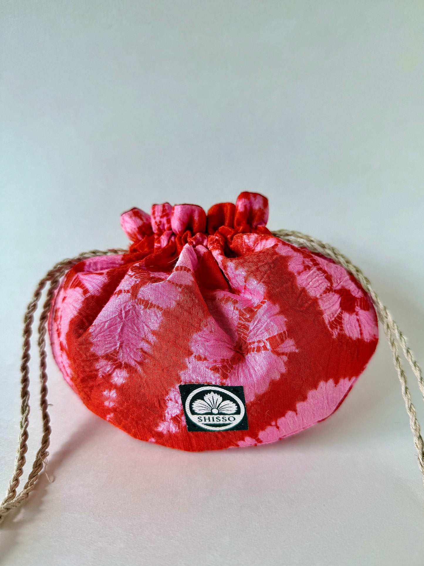 Red and pink shibori silk pouch cinched at the top with hemp drawstrings