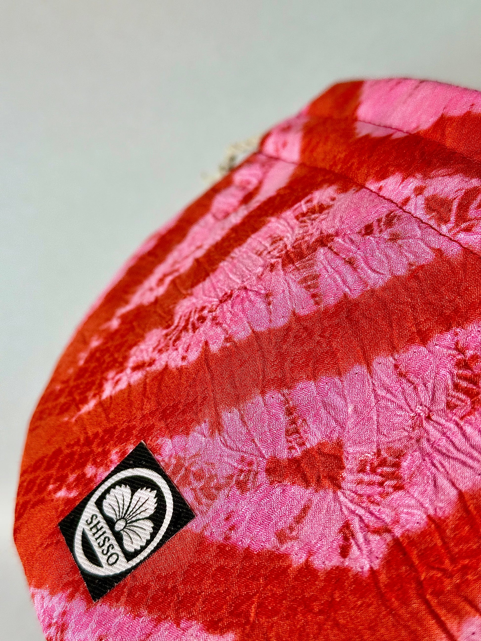 Close up view of ripple texture of red and pink upcyled kimono silk drawstring bag with red top stitching