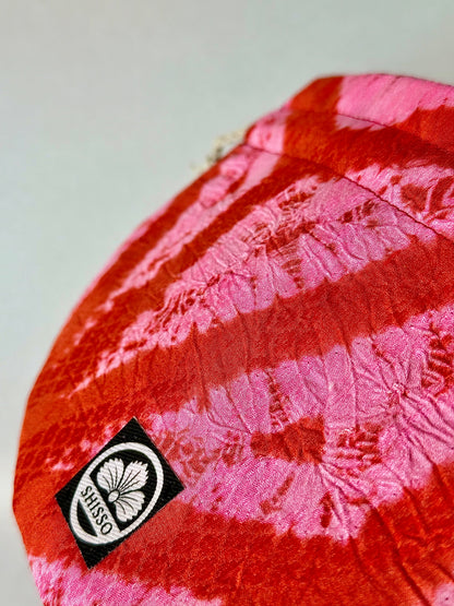 Close up view of ripple texture of red and pink upcyled kimono silk drawstring bag with red top stitching