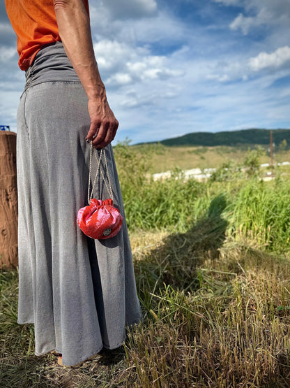 Red and pink kimono silk drawstring pouch being carried in the hand by natural hemp drawstrings in nature