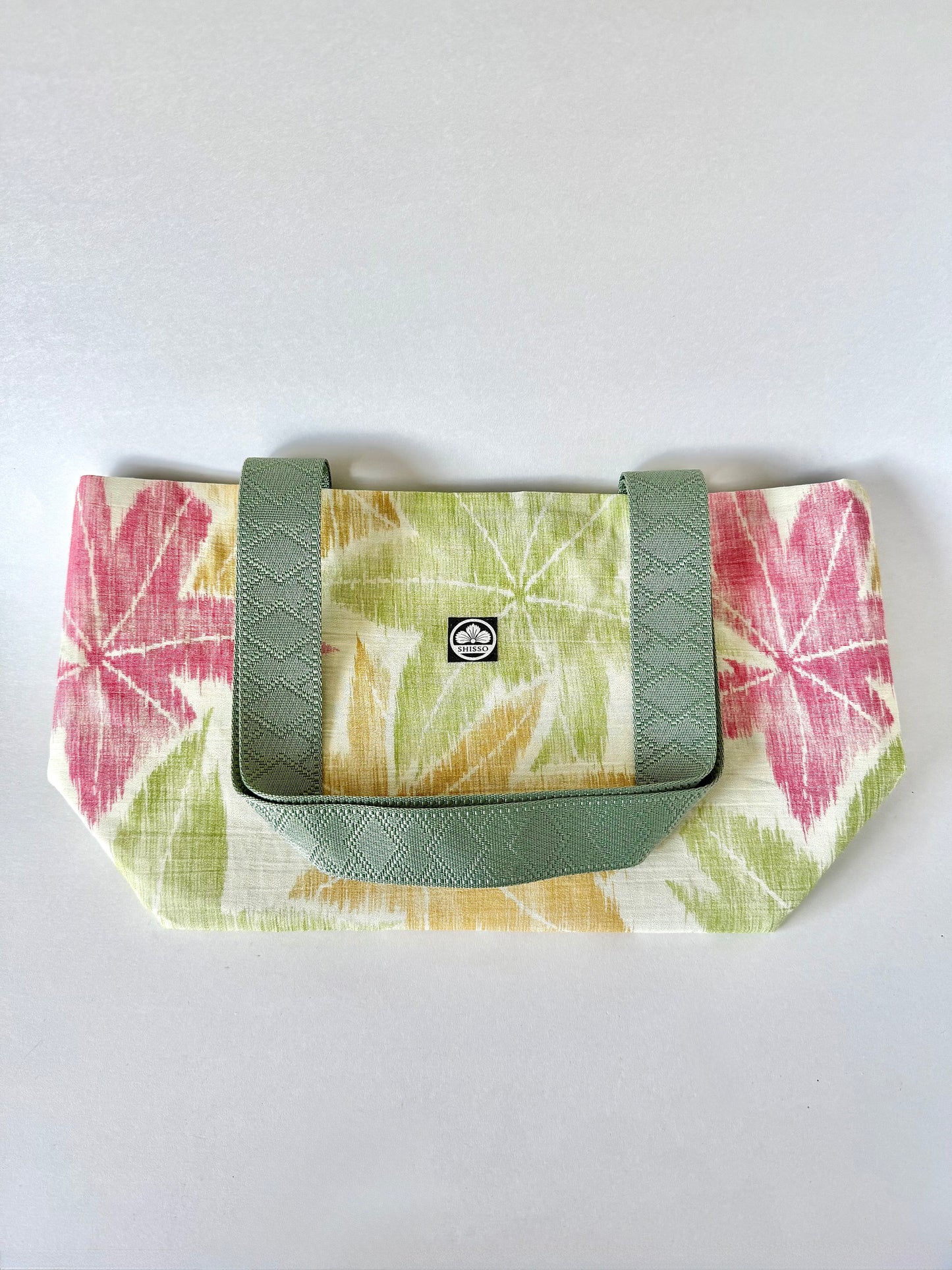 flat laying kimono silk tote bag with textured webbing handles folded on top