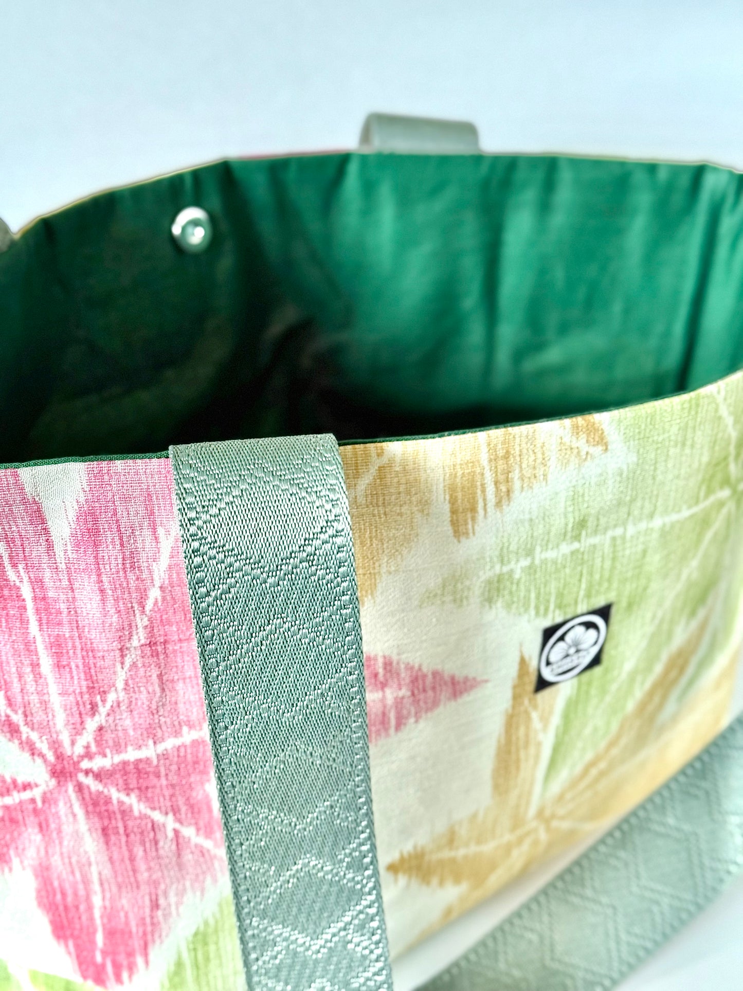 Close up view of dark sage green webbing handles on woven kimono silk tote 